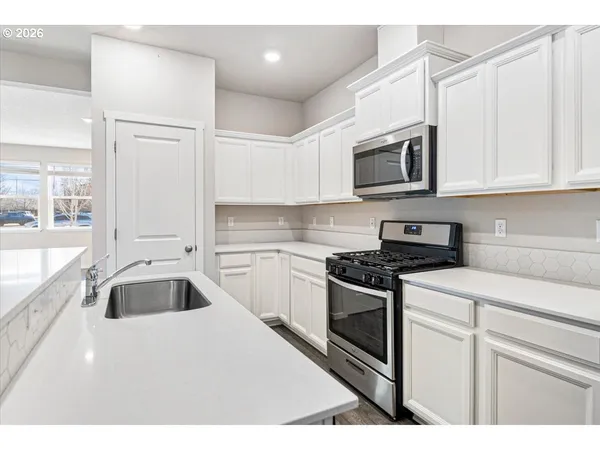 a kitchen with stainless steel appliances granite countertop a sink and cabinets with wooden floor