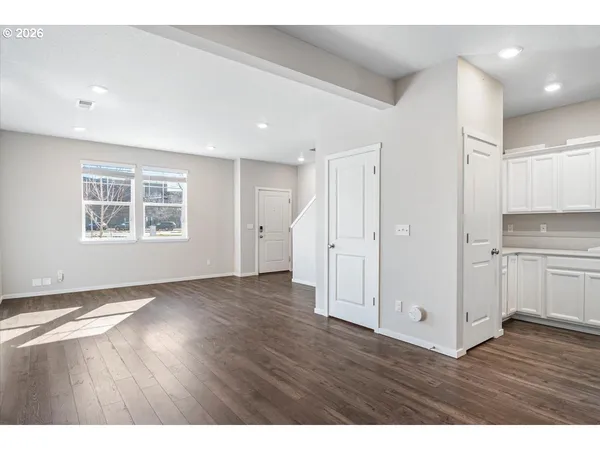 a view of an empty room with window and wooden floor