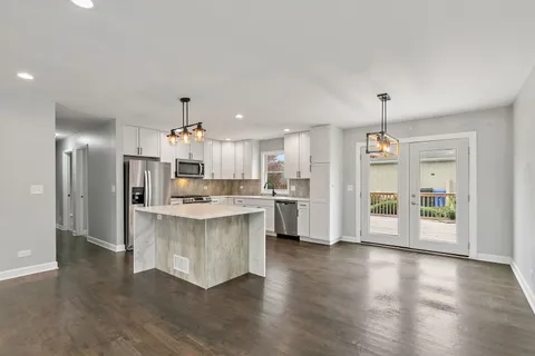 a kitchen with stainless steel appliances kitchen island wooden floors stove and white cabinets