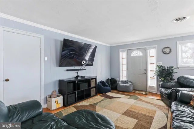 a living room with furniture kitchen view and a wooden floor