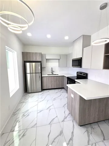 a kitchen with granite countertop a refrigerator and a stove top oven