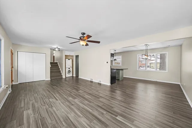 an empty room with wooden floor chandelier and windows