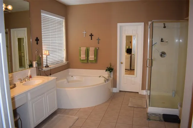 a spacious bathroom with a tub sink and mirror