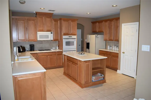 a kitchen with a sink a stove a refrigerator a center island and cabinets