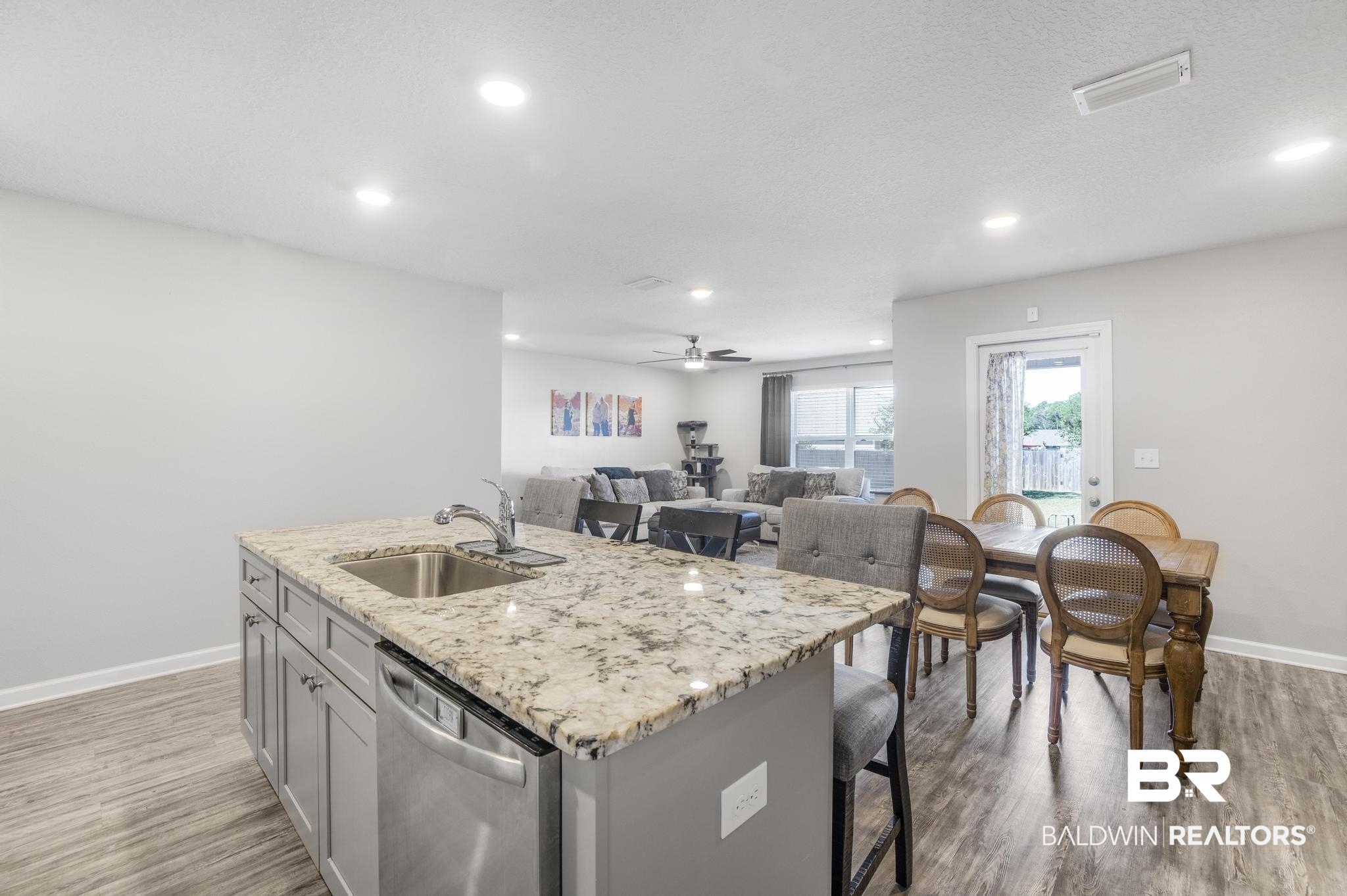 10738 Ridgeview Drive Mobile, AL 36608 - Photo 7 of 48 Kitchen with light stone countertops, a kitchen island with sink, gray cabinets, stainless steel dishwasher, and light wood-type flooring