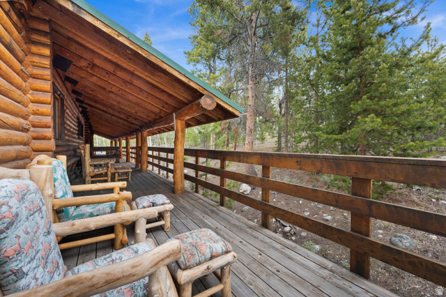 4725 Pine Ridge Road Evanston, UT 82930 - Photo 34 of 82 Expansive covered wood porch featuring a log cabin exterior, exposed wood ceiling, and wood railing
