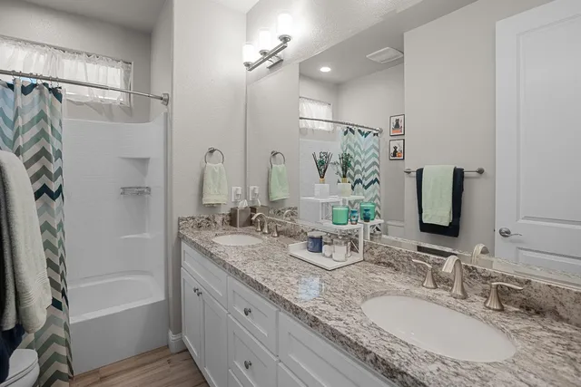 a bathroom with a granite countertop sink mirror toilet and bathtub