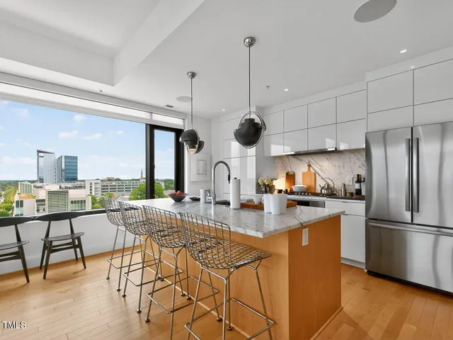 a kitchen with stainless steel appliances granite countertop a stove a refrigerator a oven a sink with island chairs and wooden floor