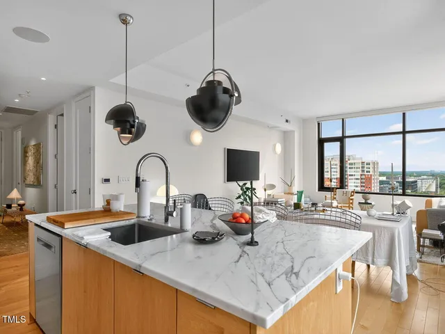 a kitchen with stainless steel appliances granite countertop a sink a stove and a dining table with wooden floor