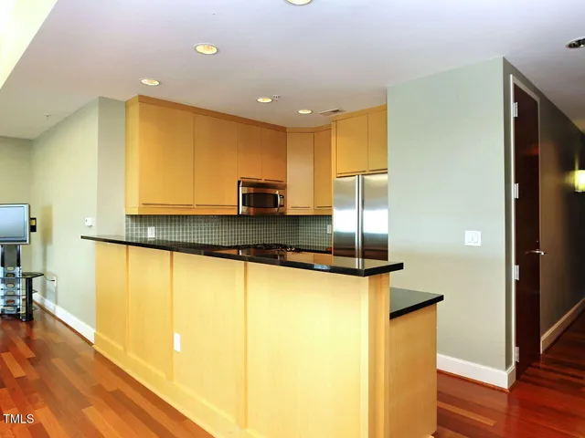 a kitchen with stainless steel appliances granite countertop a sink and a refrigerator