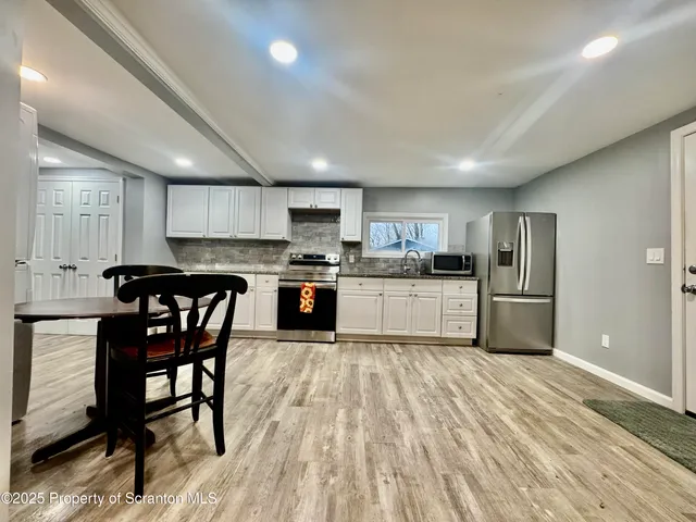 a kitchen with stainless steel appliances granite countertop a stove top oven a sink dishwasher a dining table and chairs with wooden floor