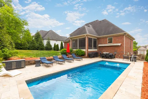 a view of a house with backyard swimming pool and sitting area