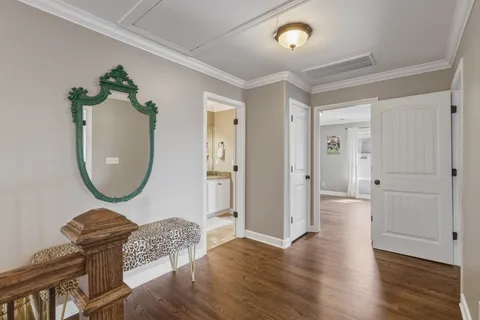 a view of a hallway with wooden floor staircase and a living room