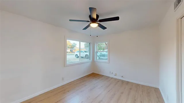 a view of empty room with wooden floor and fan