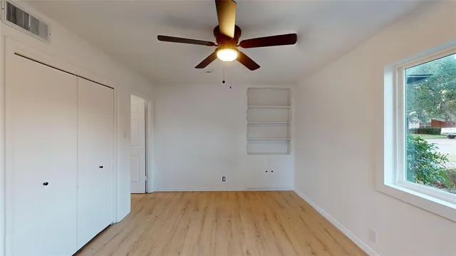 a view of empty room with wooden floor and fan