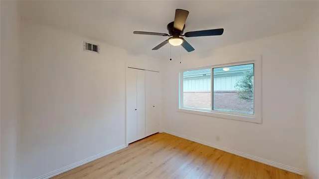 a view of empty room with wooden floor and fan