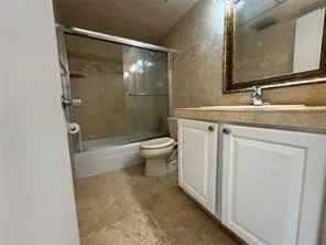 a bathroom with a granite countertop sink toilet and shower