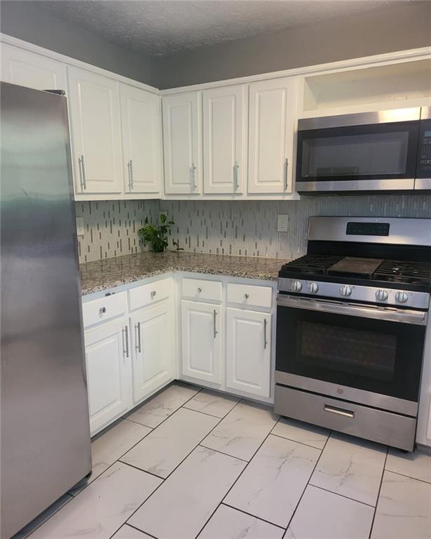 1607 Sweetgum Hill Decatur, GA 30032 - Photo 22 of 25 a kitchen with white cabinets and appliances