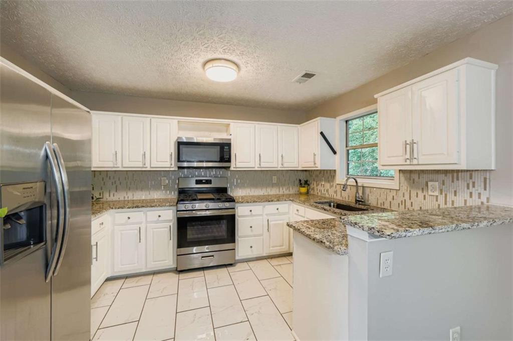 1607 Sweetgum Hill Decatur, GA 30032 - Photo 4 of 25 a kitchen with cabinets stainless steel appliances a sink and a counter top space