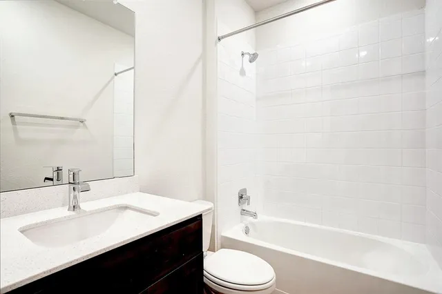 a bathroom with a bathtub shower sink vanity mirror and toilet