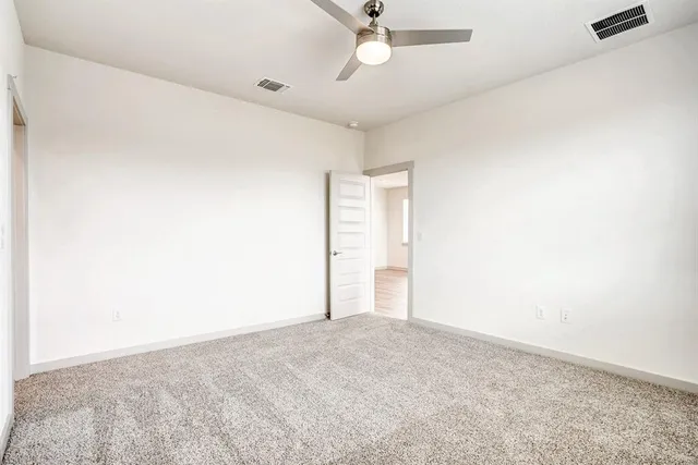 an empty room with a ceiling fan and a window