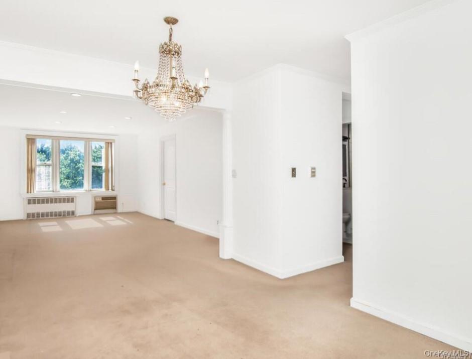 245 Rumsey Road, Unit 4K Yonkers, NY 10701 - Photo 2 of 3 Empty room with carpet floors, radiator, a chandelier, and ornamental molding