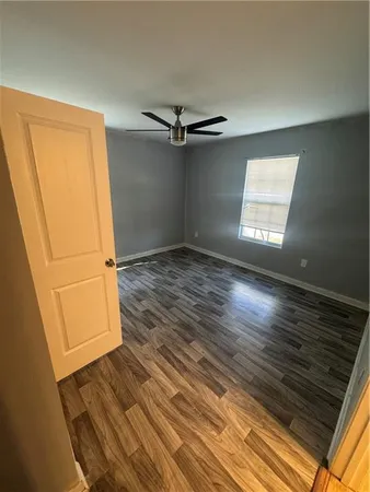 an empty room with wooden floor cabinet and windows