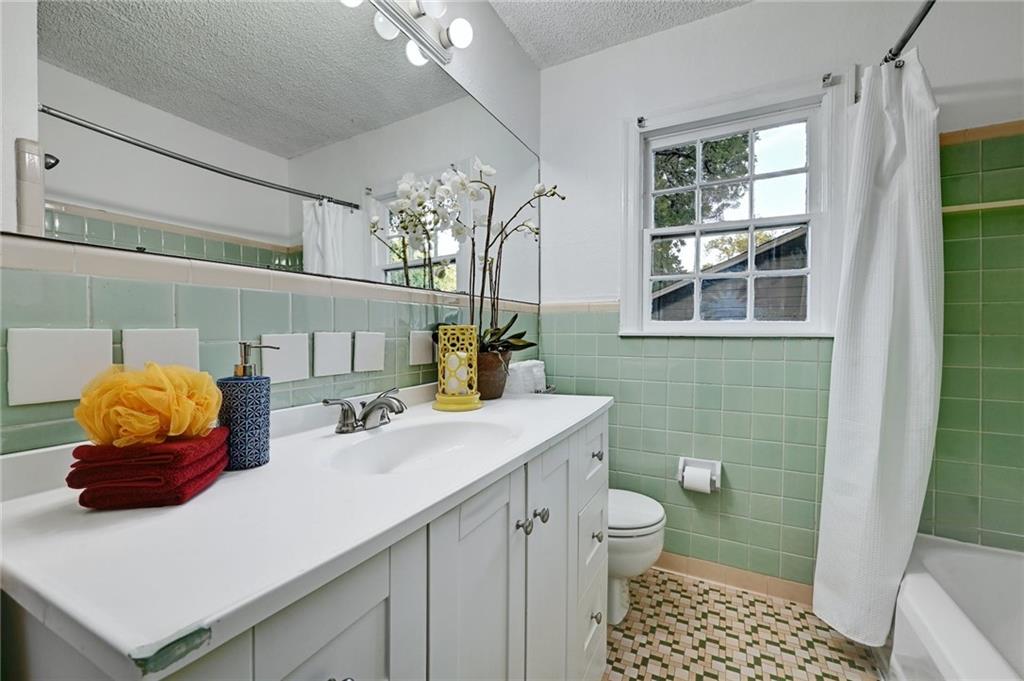3207 Breeze Terrace, Unit A Austin, TX 78722 - Photo 13 of 18 Secondary Bathroom with vanity, a textured ceiling, shower / tub combo with curtain, wainscoting, and tile walls