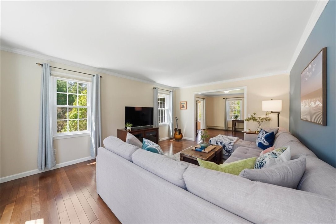 32 Lisa Lane Hopkinton, RI 02832 - Photo 18 of 50 A warm and inviting living room features rich Brazilian redwood floors, abundant natural light, and a comfortable, open layout designed for both relaxation and entertaining.