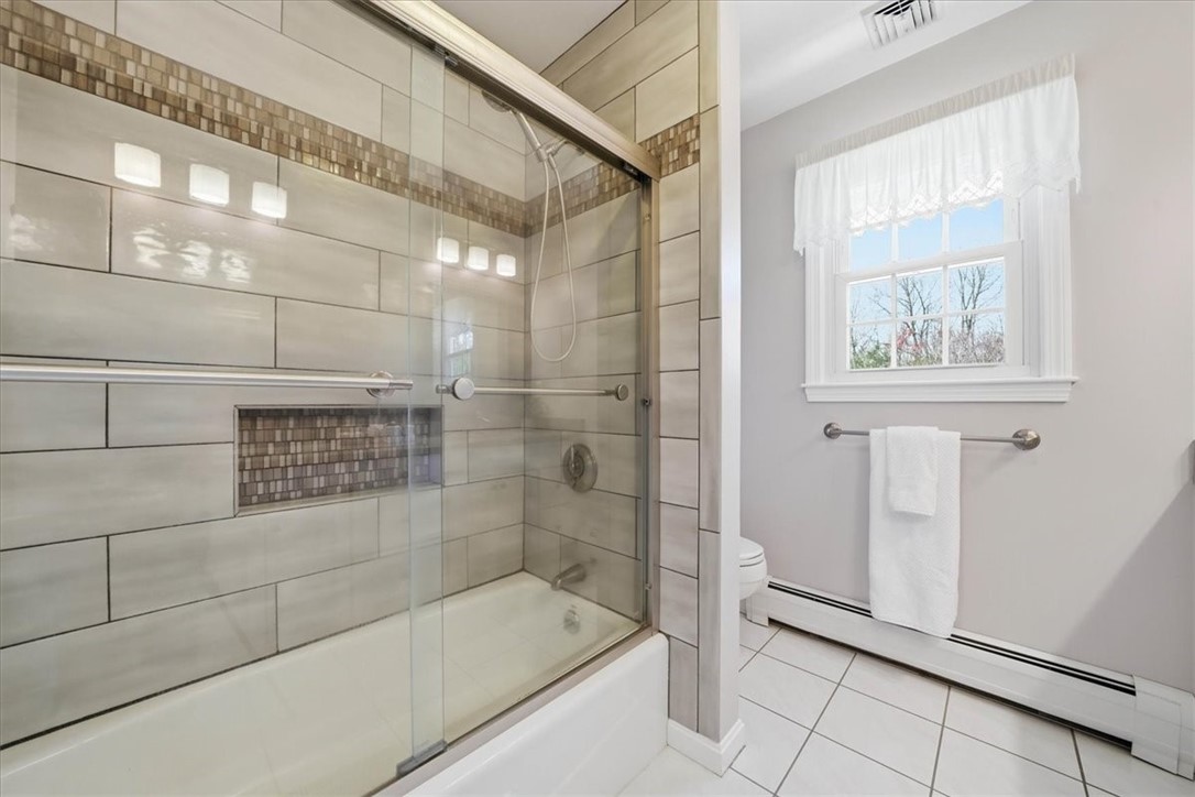 32 Lisa Lane Hopkinton, RI 02832 - Photo 26 of 50 The tiled walk-in shower/bath showcases a clean, modern design w/ elegant tilework & glass enclosure, creating a spa-like feel. Bright, airy & thoughtfully finished, this bathroom offers both everyday comfort & elevated design.