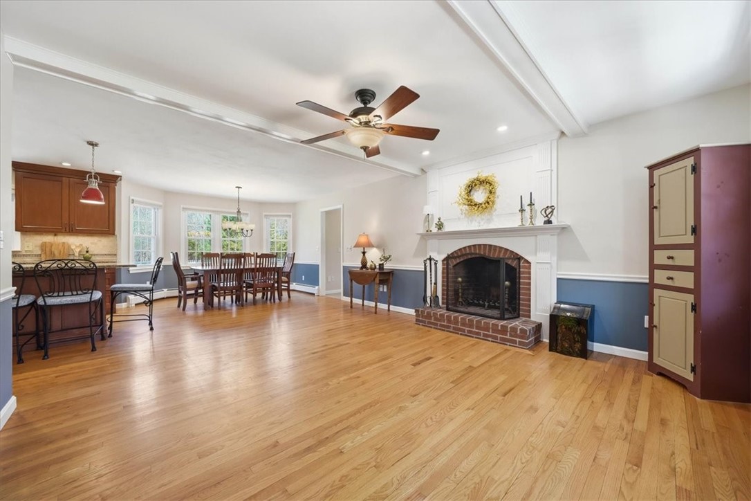 32 Lisa Lane Hopkinton, RI 02832 - Photo 8 of 50 A stunning, light-filled open living space sets the tone, anchored by rich hardwood flooring, detailed crown molding, and a classic brick fireplace with custom mantel.