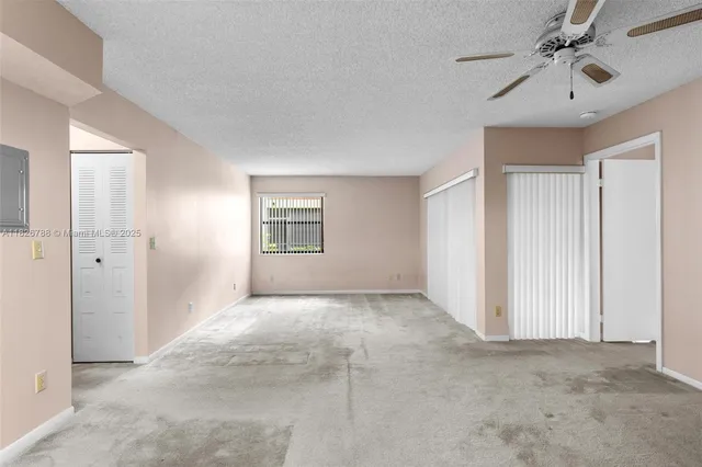 a view of a livingroom with a chandelier fan and windows