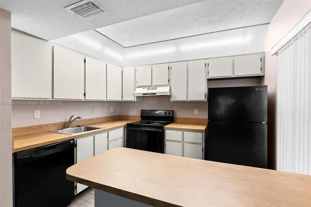 a kitchen with a sink a stove a refrigerator and black cabinets