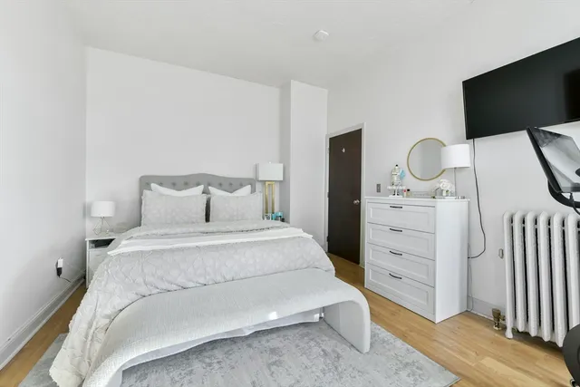 a bedroom with a bed and a flat tv screen on dresser