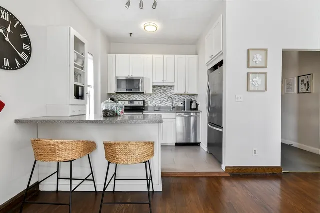 a kitchen with stainless steel appliances granite countertop a refrigerator a stove a sink dishwasher and white cabinets with wooden floor