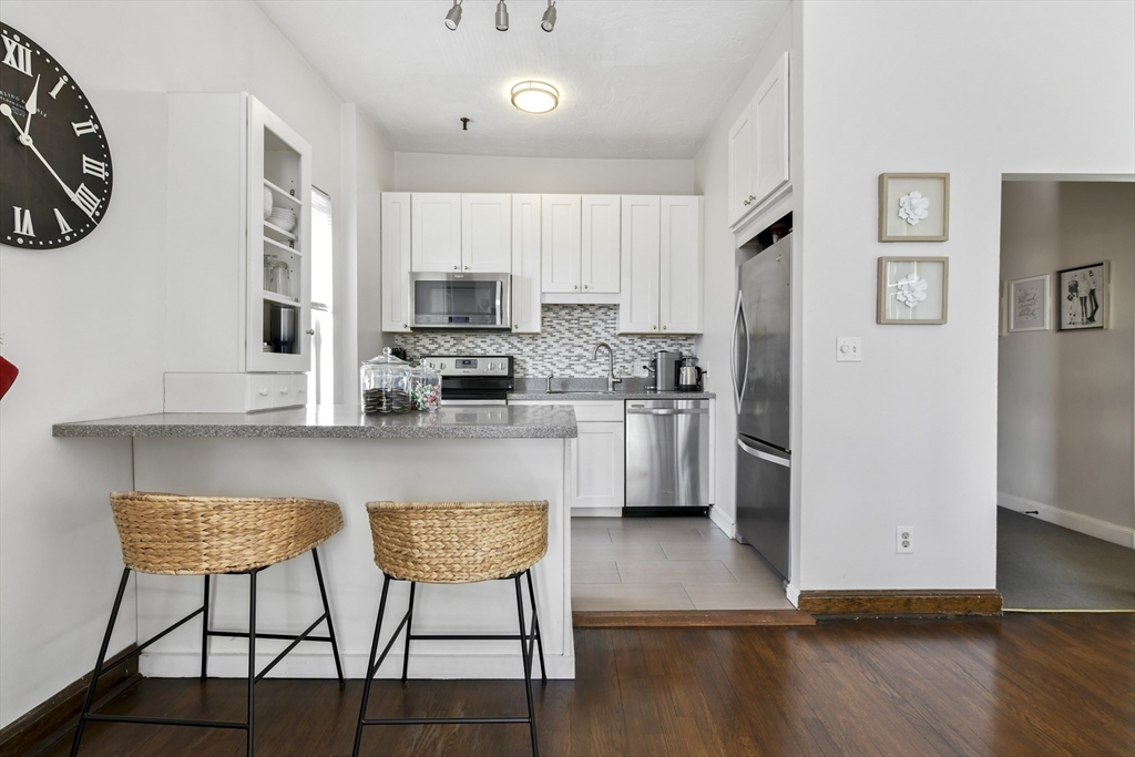 411 Marlborough Street, Unit 9 Boston, MA 02115 - Photo 8 of 20 a kitchen with stainless steel appliances granite countertop a refrigerator a stove a sink dishwasher and white cabinets with wooden floor