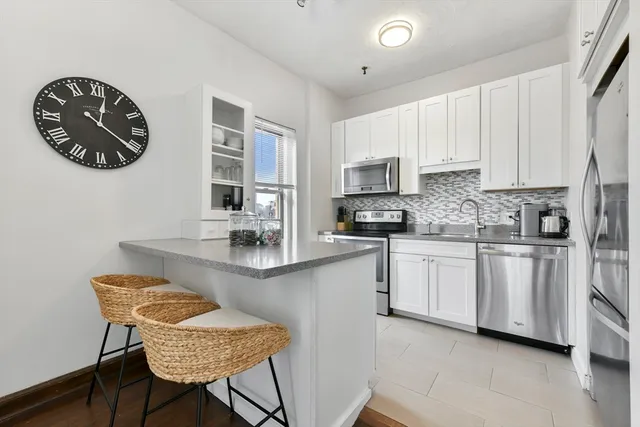 a kitchen with stainless steel appliances granite countertop a sink a stove a microwave a dining table and chairs