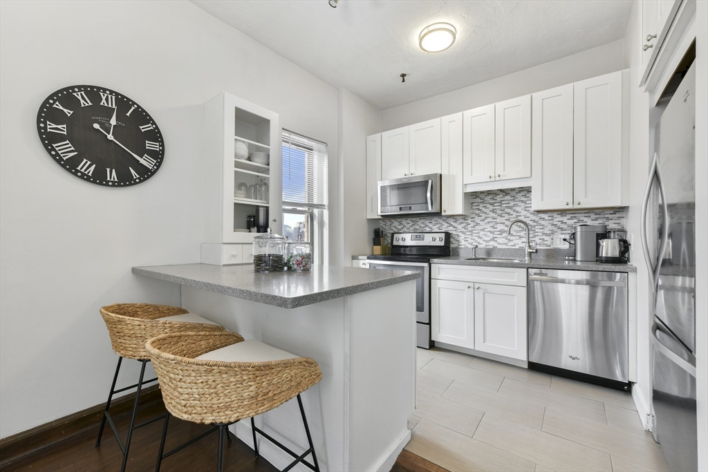 411 Marlborough Street, Unit 9 Boston, MA 02115 - Photo 9 of 20 a kitchen with stainless steel appliances granite countertop a sink a stove a microwave a dining table and chairs
