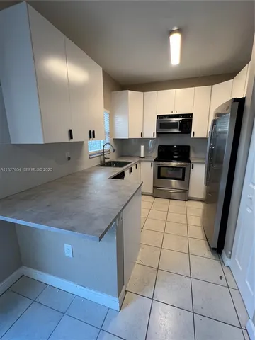 a kitchen with kitchen island granite countertop a sink a counter top space appliances and cabinets