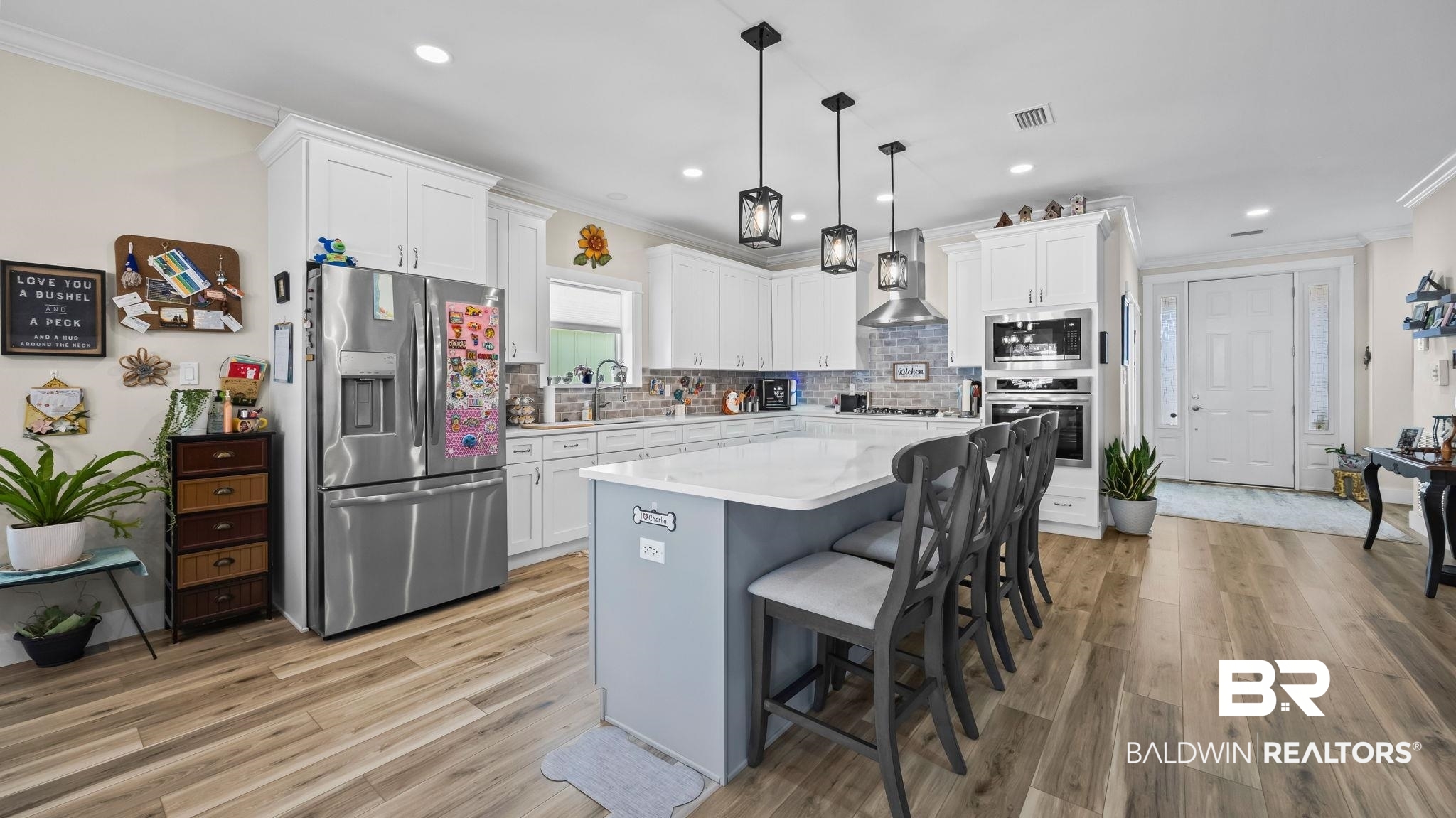 8013 Carmel Circle Foley, AL 36535 - Photo 10 of 49 Two tone kitchen with crown molding, stainless steel appliances, a kitchen breakfast bar, hanging light fixtures, and light wood-style floors