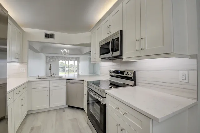 a kitchen with white cabinets stainless steel appliances and sink