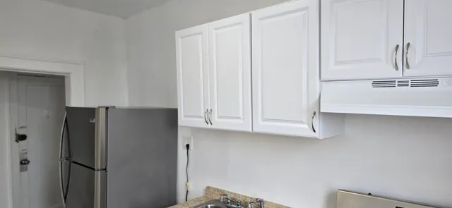 a close view of a refrigerator in kitchen and white cabinets