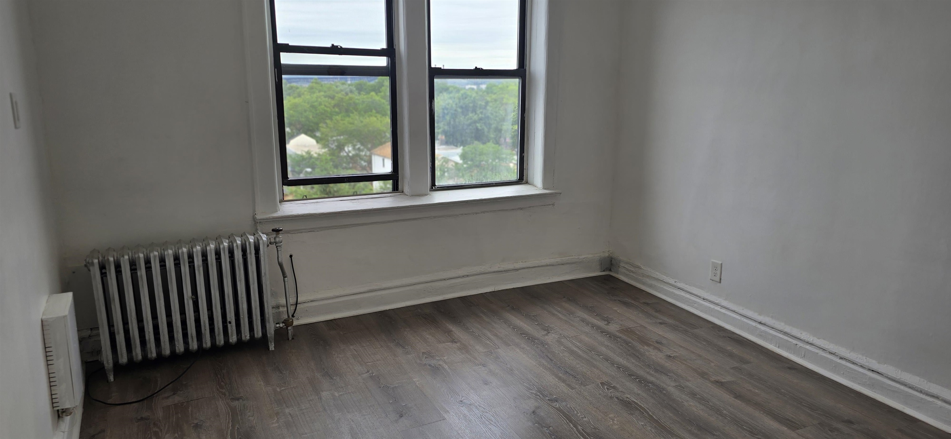 277 Harrison Avenue, Unit E4 Jersey City, NJ 07304 - Photo 8 of 13 an empty room with wooden floor and windows