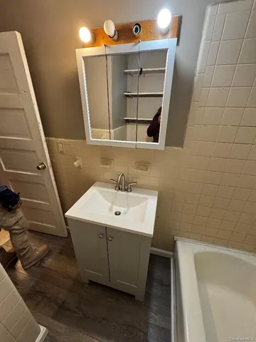 a bathroom with a sink and mirror with bathtub