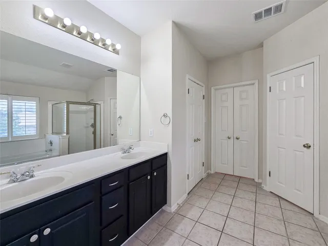 a spacious bathroom with a double vanity sink a mirror and a