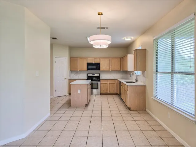 a kitchen with stainless steel appliances granite countertop a sink a stove a refrigerator cabinets and a dining table