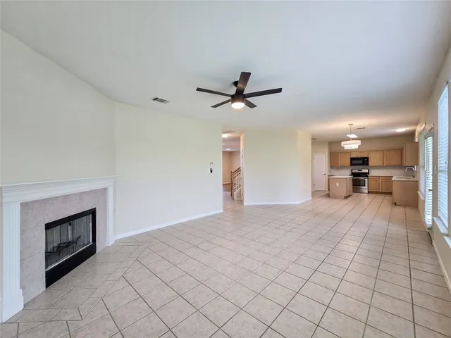 a view of a livingroom with a fireplace a ceiling fan a fireplace and windows