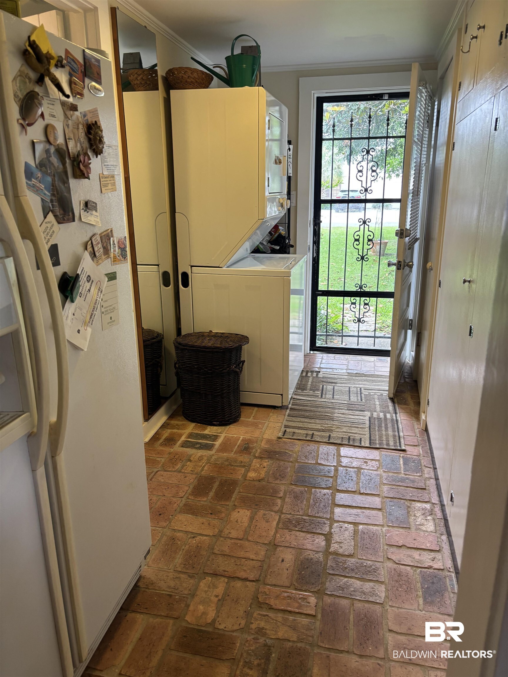 216 West Orange Avenue Foley, AL 36535 - Photo 31 of 37 Doorway with stacked washing machine and dryer and brick floors