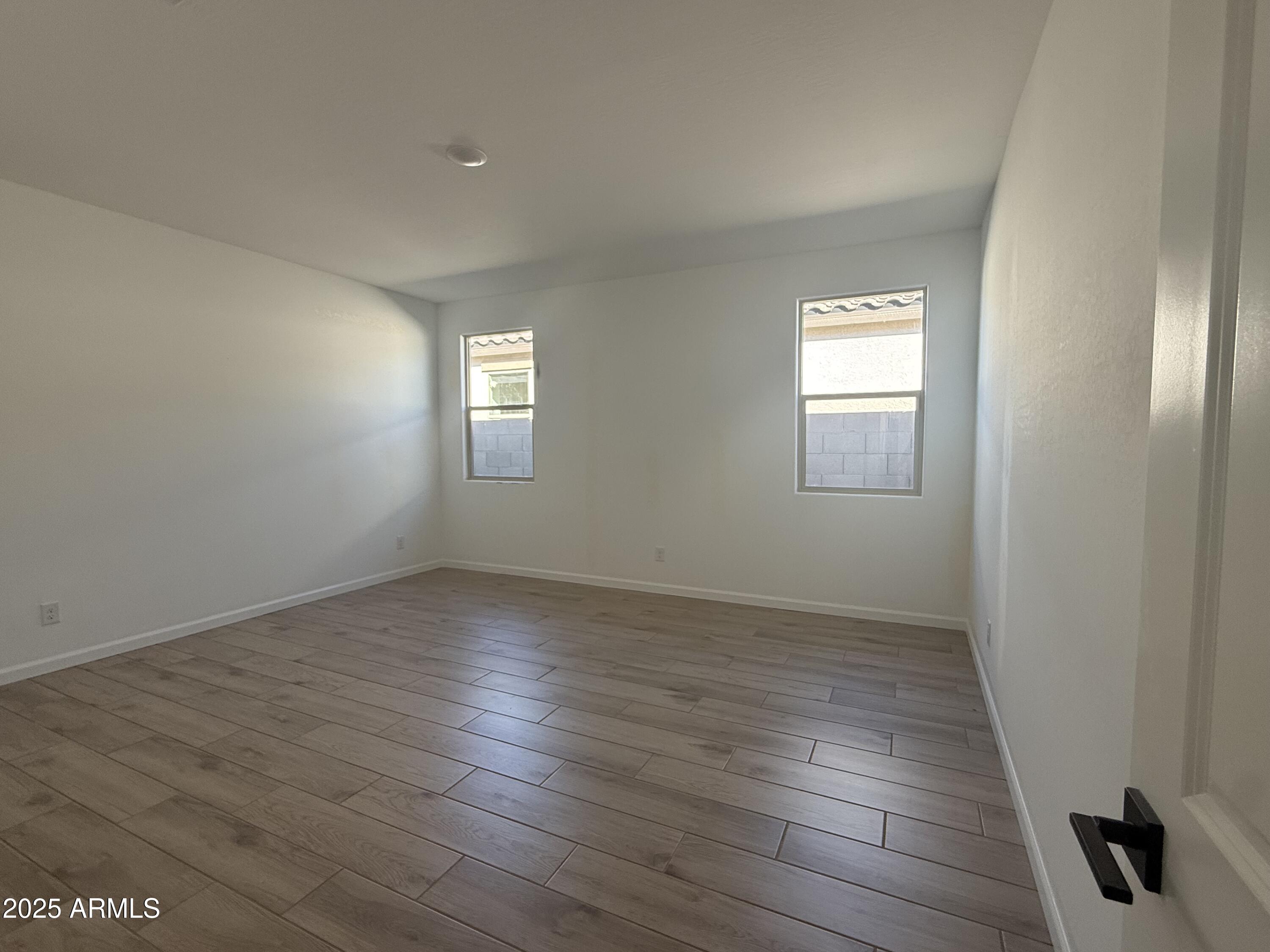 9620 West Tamarisk Avenue Tolleson, AZ 85353 - Photo 10 of 32 an empty room with wooden floor and windows