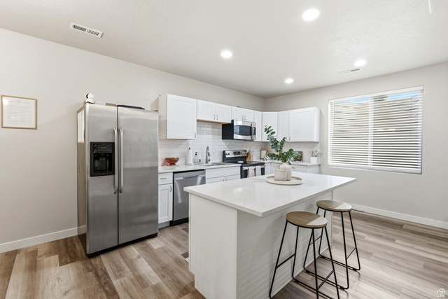 1434 West Stable Street Lindon, UT 84042 - Photo 39 of 76 Kitchen with stainless steel appliances, white cabinetry, a kitchen bar, a kitchen island, and light wood-style flooring